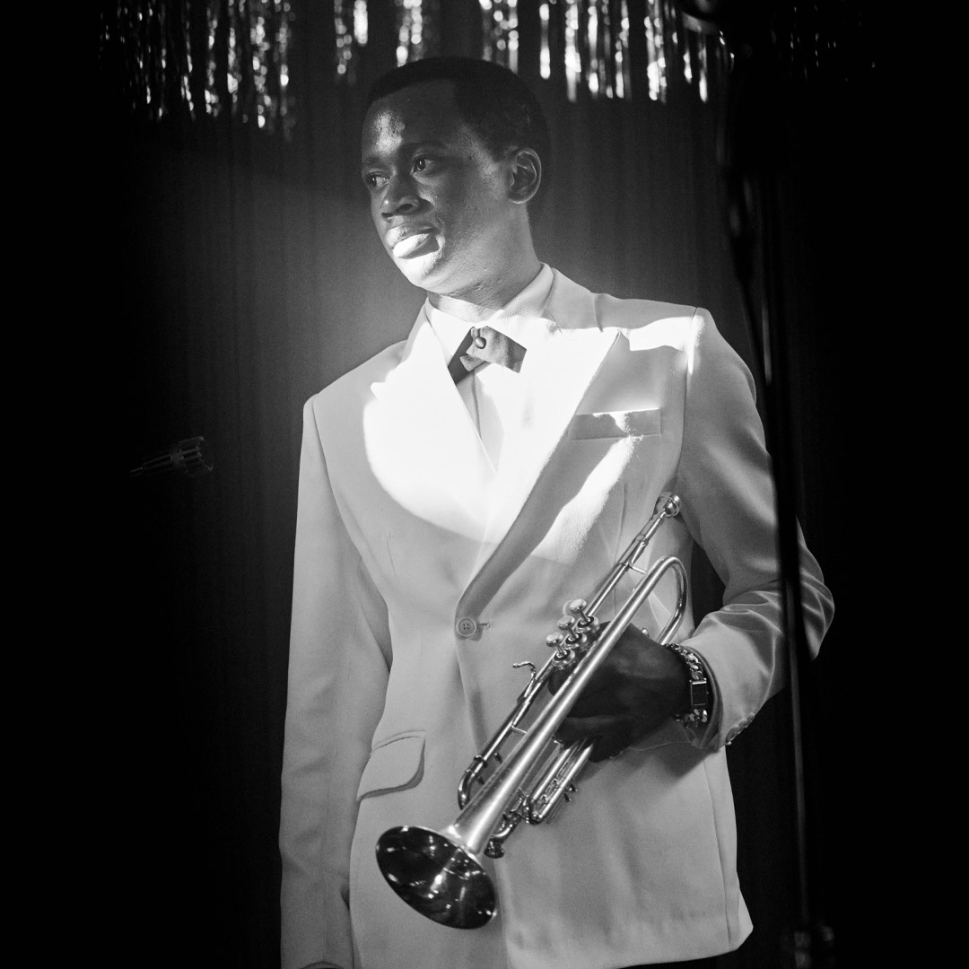 Grayscale photo of same musician holding trumpet